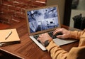 Man monitoring modern cctv cameras on laptop, closeup. Home security system