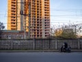 A man on a moped parked on the side of the road. at the building under construction. Modern industrial area. Two-wheeled transport