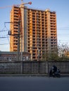 A man on a moped parked on the side of the road. at the building under construction. Modern industrial area. Two-wheeled transport