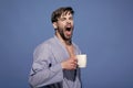 Man with morning drink. Bachelor in dressing gown yawn with mug. Morning routine concept. Breakfast, coffee or tea time Royalty Free Stock Photo