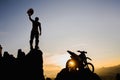 Man with motocross bike against beautiful lights, silhouette of a man with motocross motorcycle On top of rock high mountain at Royalty Free Stock Photo