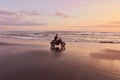 Man And Motorcycle On Ocean Beach At Beautiful Tropical Sunset. Biker Silhouette On Motorbike.