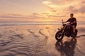 Man And Motorcycle On Ocean Beach At Beautiful Tropical Sunset. Handsome Biker On Motorbike.