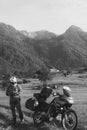 Man motorcyclist Looking for something in the trunk. Alpine mountains on background. Biker lifestyle, world traveler. Summer day.