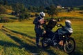 Man motorcyclist Looking for something in the trunk. Alpine mountains on background. Biker lifestyle, world traveler. Summer sunny