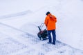 Man with motorized track drive snowblower clears snow, a snowblower on a snowy road detail. Motor machine for removing