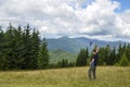 Man on the mountain meadow raised his hand with trekking poles enjoying the mountain view. Carpathians
