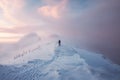 Man mountaineer walking with footprint on snowy mountain and colorful sky in blizzard at sunrise Royalty Free Stock Photo