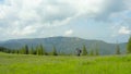 A man in the mountains with a backpack on his back walks along a grassy slope Royalty Free Stock Photo