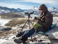 Man in the mountains with binoculars and telescope