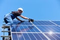 Man mounting modern solar batteries on house`s roof. Royalty Free Stock Photo