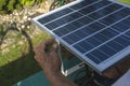 A man mounting a small 50 watt Polycrystalline solar panel on the eaves of a roof of a bungalow house Royalty Free Stock Photo