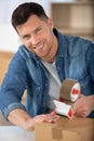 man moving in new apartment packing and taping boxes Royalty Free Stock Photo