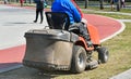 Man is mowing the grass next to the running track Royalty Free Stock Photo