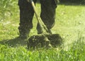 The man mowing green wild grass field using brush cutter mower or power tool string lawn trimmer Royalty Free Stock Photo