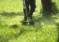 The man mowing green wild grass field using brush cutter mower or power tool string lawn trimmer Royalty Free Stock Photo