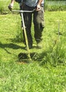 The man mowing green wild grass field using brush cutter mower or power tool string lawn trimmer Royalty Free Stock Photo