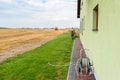 A man mowing the lawn with a grass trimmer, along the facade of the house, he can be seen from behind. A coiled garden hose is vis Royalty Free Stock Photo