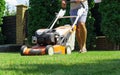 Man mowing the lawn with lawn mower in summer. Spring season sunny lawn mowing in the garden. Royalty Free Stock Photo