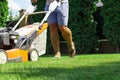 Man mowing the lawn with lawn mower in summer. Spring season sunny lawn mowing in the garden. Royalty Free Stock Photo