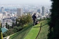 Man mowing a lawn using a lawnmower in Bahai Gardens on the Haifa panorama background Royalty Free Stock Photo