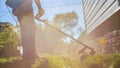 Man mowing tall grass with electric or petrol lawn trimmer in backyard. Gardening care tools and equipment. Process of Royalty Free Stock Photo