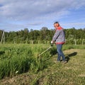 Man mows the grass with a trimmer, tall grass in a meadow, handmade in the garden Royalty Free Stock Photo