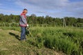 Man mows the grass with a trimmer, tall grass in a meadow, handmade in the garden Royalty Free Stock Photo