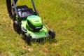 A man mows on green grass used by electric lawn mower Royalty Free Stock Photo