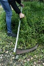 Man mows the grown grass with a scythe