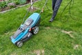 A man mows the lawn in his garden with an electric mower, close-up Royalty Free Stock Photo