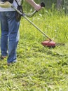 Man mows tall green grass petrol trimmer Royalty Free Stock Photo