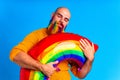 man with multi colored bead hugging balloon inflatable in blue background studio