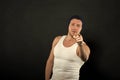 Man with muscular arms and tight t shirt pointing forward. Macho on confident face looks brutal, black background. Man