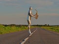 Man musician saxophonist in full body-hugging silver, silver electric suit holding golden alto saxophone, jumped and hovered in