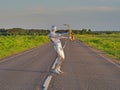 Man musician saxophonist in full body-hugging silver and silver electric suit holding golden alto saxophone, standing on empty