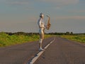 Man musician saxophonist in full body-hugging silver and silver electric suit holding golden alto saxophone, standing on empty