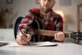 Man musician writing song with guitar at home, close up.