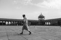 Man in muslim dress walking across the empty Jama Masjid during Ramdan