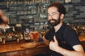 Man with a mustache and beard stands at the bar and drinks alcohol from a glass. Royalty Free Stock Photo