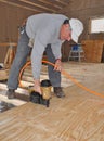 Man nailing plywood floor with nail gun