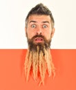 Man with spikelet in beard on white and orange background.