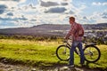 A man in nature with a bicycle on the background of mountains and blue sky Royalty Free Stock Photo