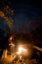 Man near the burning bonfire in the night under a starry sky Royalty Free Stock Photo