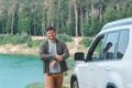 man near white suv car at the edge looking at lake with blue water Royalty Free Stock Photo