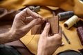 Man with needle sewing leather in workshop