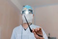 Man neurosurgeon in glasses with binary loupes for microsurgery shows a black clamp. Modern medicine. Medical instruments