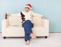 Man in a New Year's cap sits on sofa with bottle Royalty Free Stock Photo
