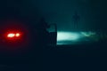 A man next to a car on an empty rural road looking at a monster alien with glowing eyes on a foggy winters night Royalty Free Stock Photo