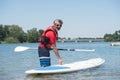 Man next to stand-up paddle board on lake Royalty Free Stock Photo